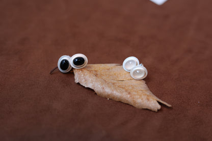 The Classic B & W Onyx Ear Stud — black and white oval studs on dried leaf