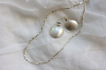 The Minimal Statement Set — round drop earrings and beaded necklace on fabric