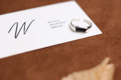 The Rectangle Signet Ring with Black Onyx — rectangular black-stone signet ring beside card
