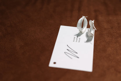The Leaves-Earrings — leaf-shaped hoops standing beside card