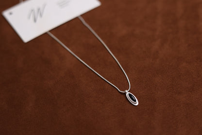 The B & W Onyx Necklace — black oval pendant necklace beside card