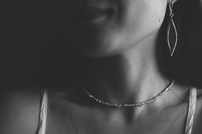 Handcrafted Minimalist Silver Irregular Beaded Necklace — black-and-white portrait of necklace worn with leaf earring