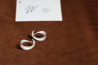 The Leaves-Earrings — leaf-shaped hoops beneath branded card