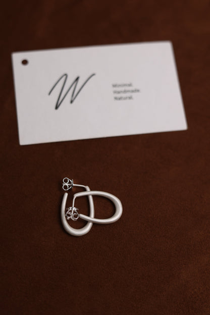 The Minimal U Ear Hoops — overlapping U-shaped hoops beside card