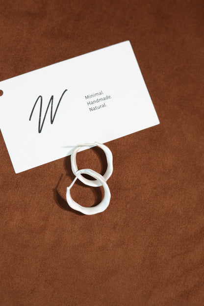 The Leaves-Earrings — leaf-shaped hoops overlapping on brown surface