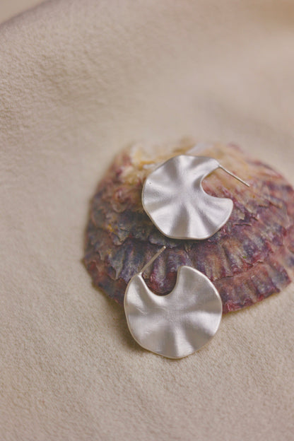 The Windmill-Earrings — windmill-shaped earrings arranged on shell