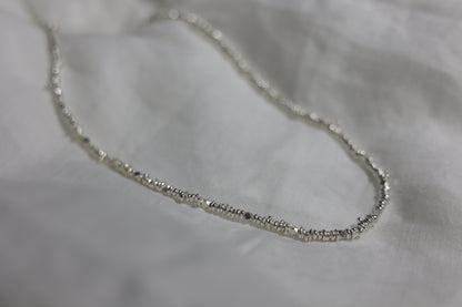 Handcrafted Minimalist Silver Irregular Beaded Necklace — irregular beaded necklace arranged on fabric
