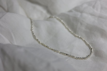Handcrafted Minimalist Silver Irregular Beaded Necklace — irregular beads on necklace arranged on fabric