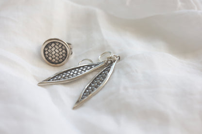 The Weaved Set — woven-pattern ring and leaf earrings arranged on fabric