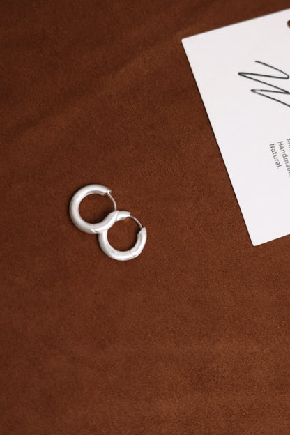 The Minimalist Basic Hoop — round hoop earrings on a wooden surface