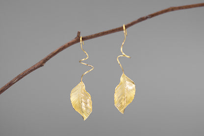 The Leaves -Earrings — gold-tone leaf earrings hanging from a twig