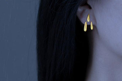 Rain Drops Earrings — gold-tone drop earring worn on an ear