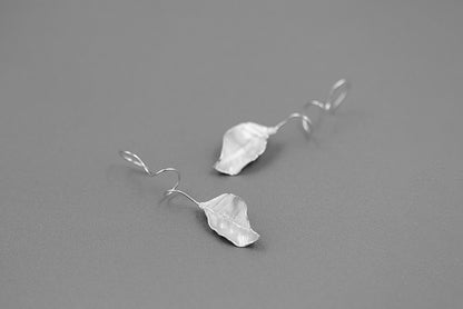 The Leaves -Earrings — silver-tone leaf earrings on grey surface