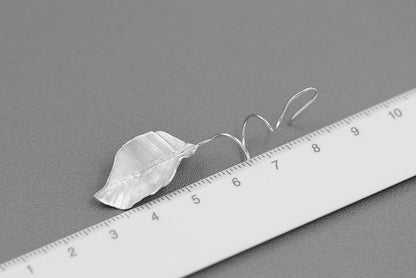 The Leaves -Earrings — silver-tone leaf earrings photographed beside a ruler