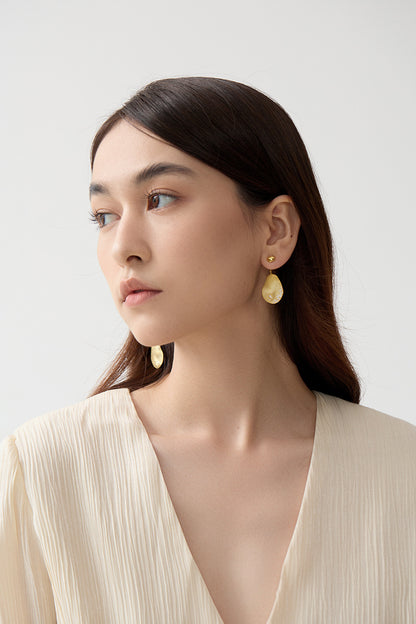 The Dune — side view of model wearing gold-tone oval drop earring